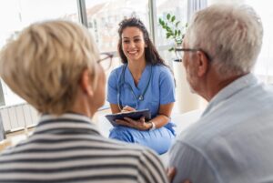 A doctor in scrubs conducts a medical review with her two senior patients