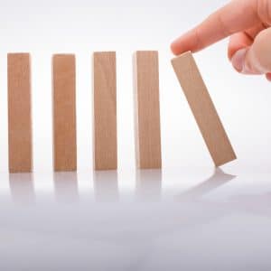 Business continuity planning represented by a hand holding wooden domino