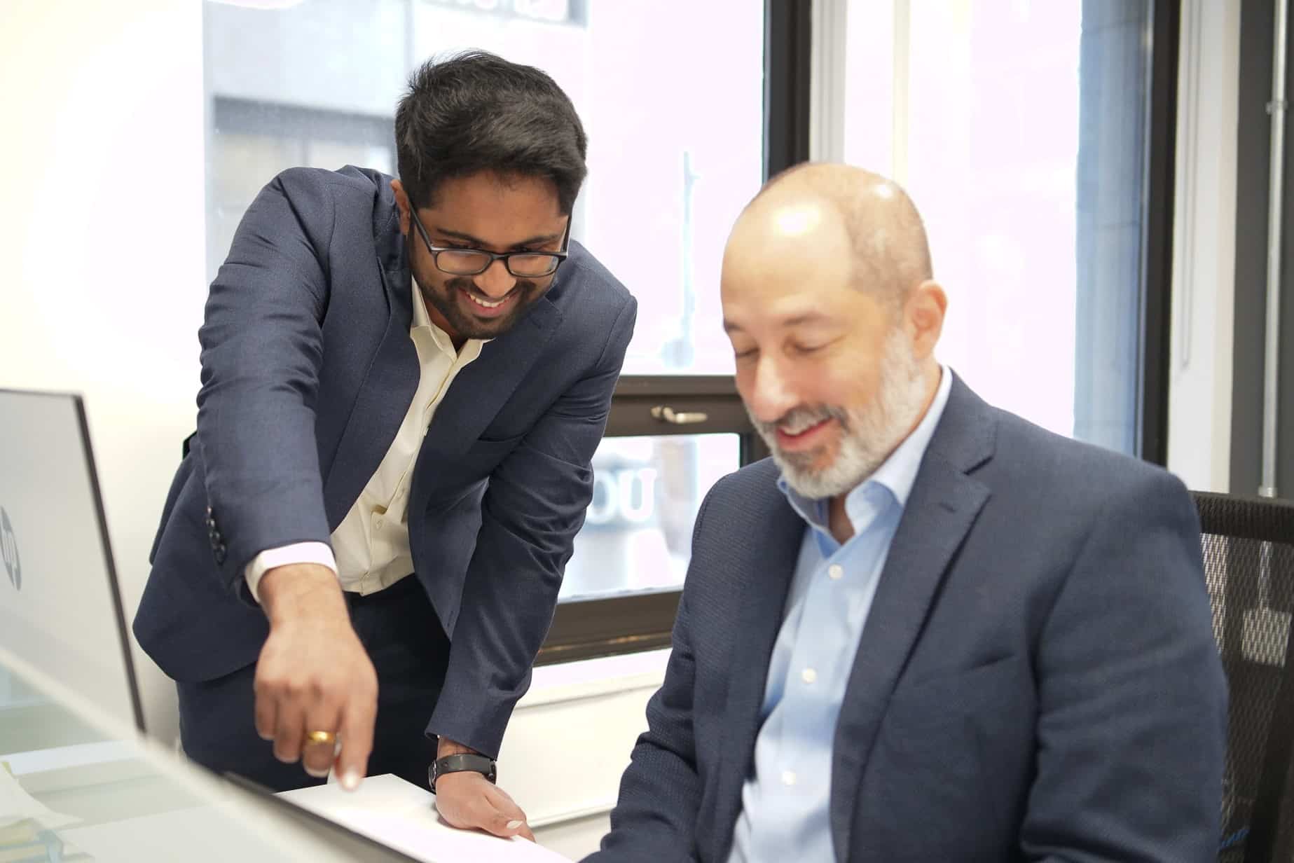 Two consultants look at a computer screen