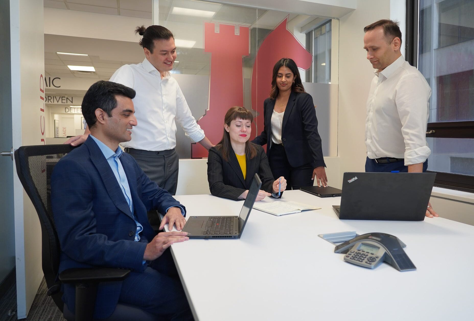 Five team members work together in a meeting room