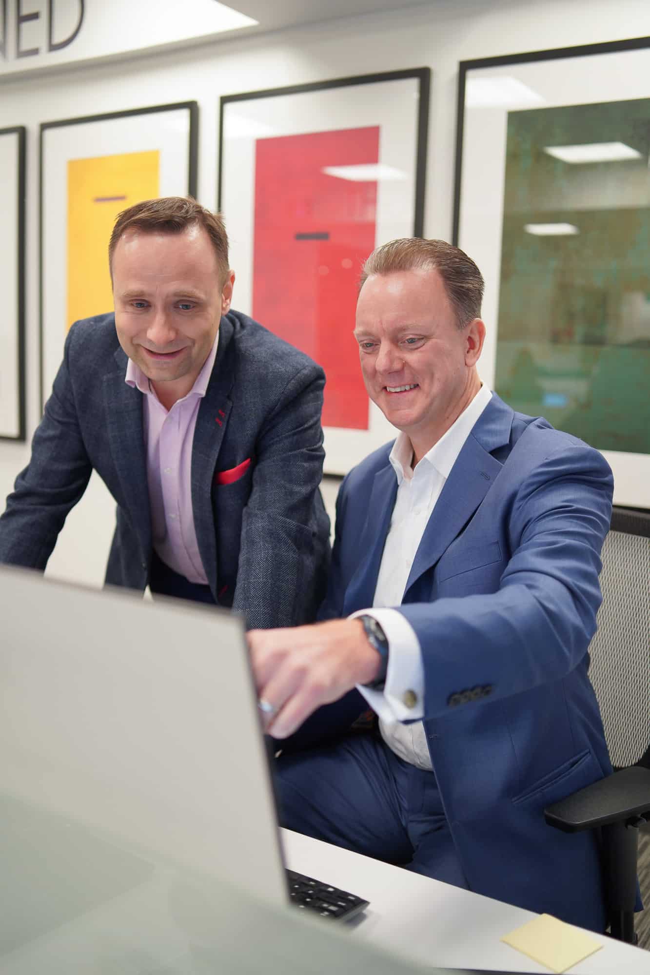 Two coworkers look at a computer screen