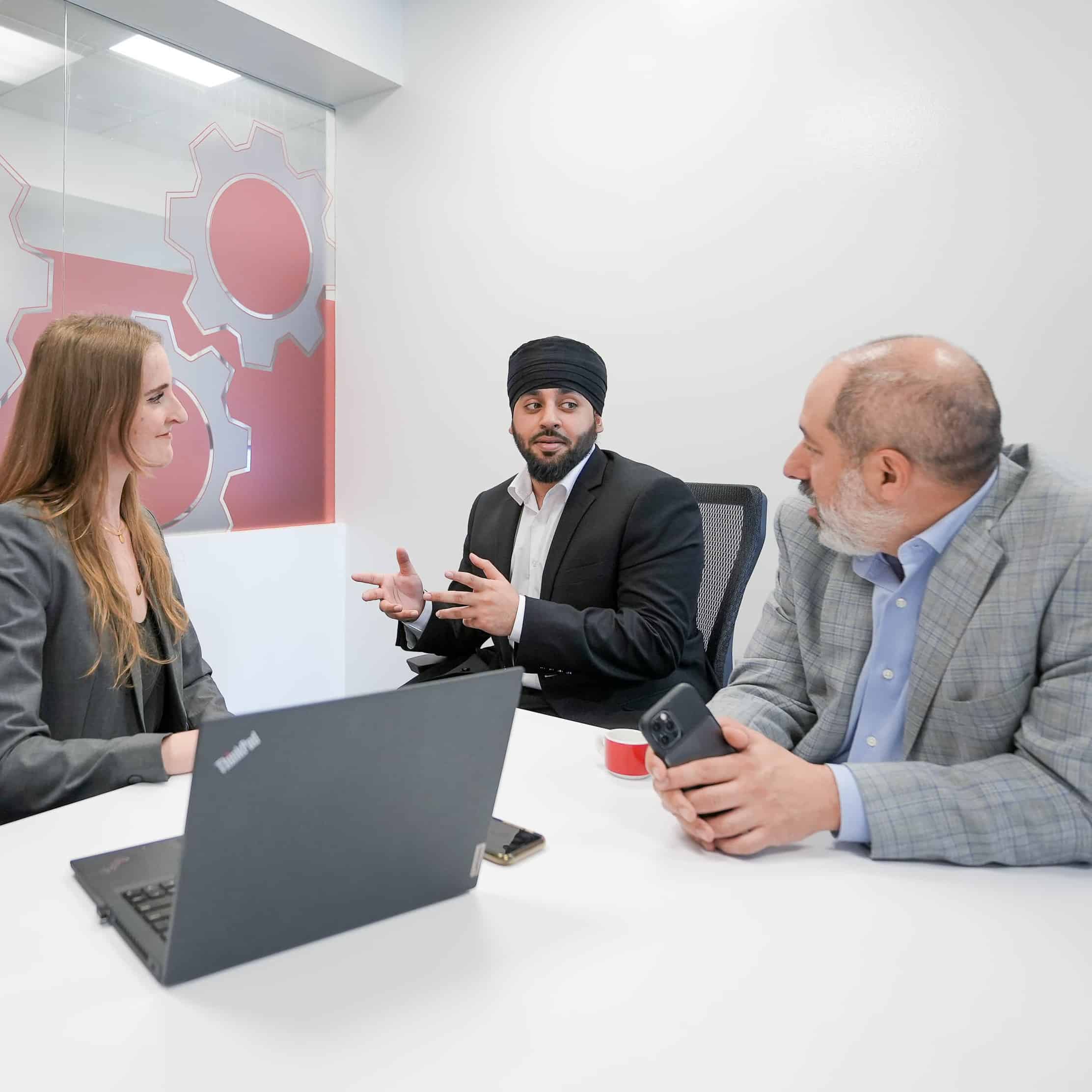 Management consultants, Gursimran and Andrew, in a meeting room with marketing manager, Courtney