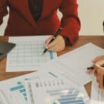 A woman and man seated at a table with charts papers