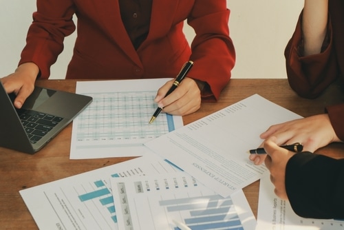 A woman and man seated at a table with charts papers