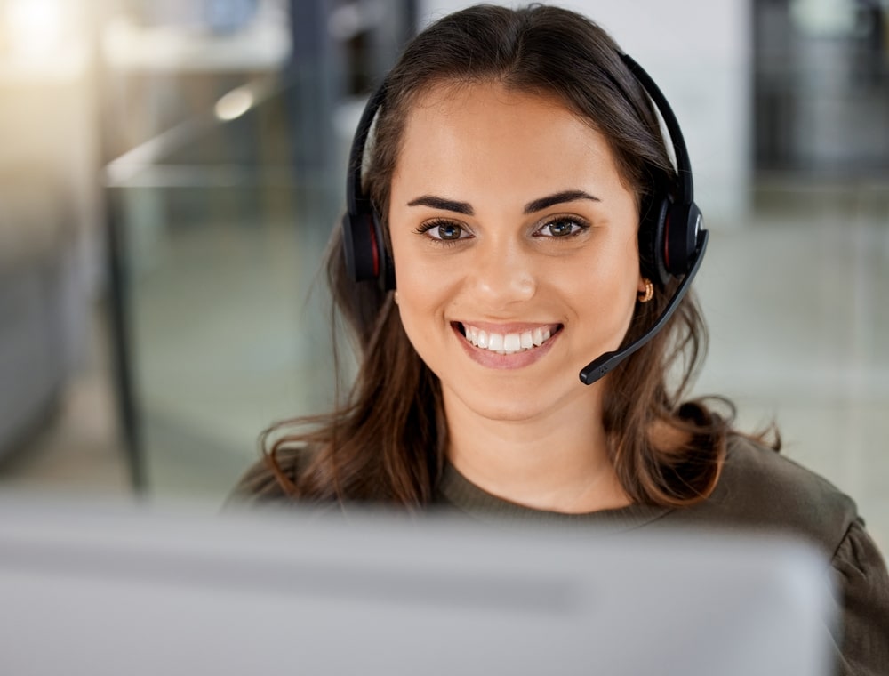 Smiling Young Woman Wearing Headphones in a Call Center Environment