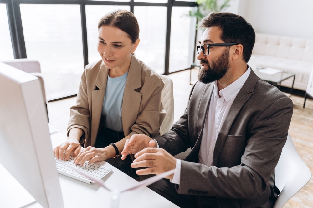 Two business people collaborating at a desktop computer.