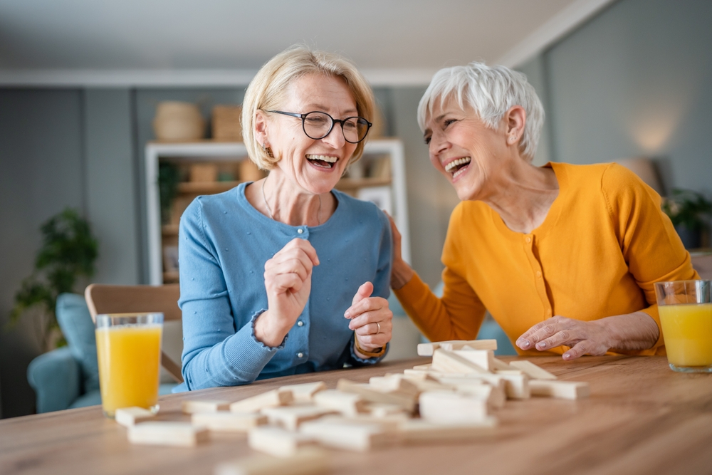 Two senior, female women, laughing and playing a game.