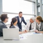 Business Team Sitting At A Table With Laptop And Documents