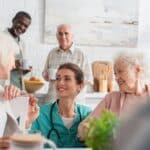 Young nurse spending time with smiling interracial patients in a senior living home environment