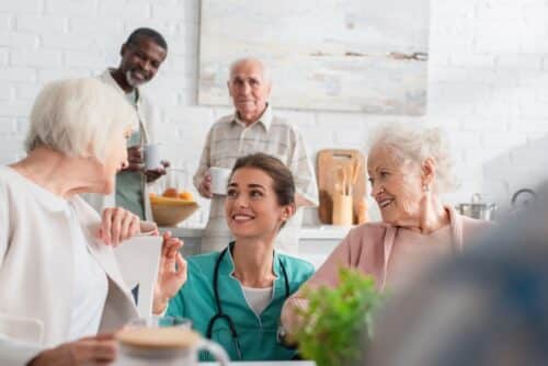 Young nurse spending time with smiling interracial patients in a senior living home environment